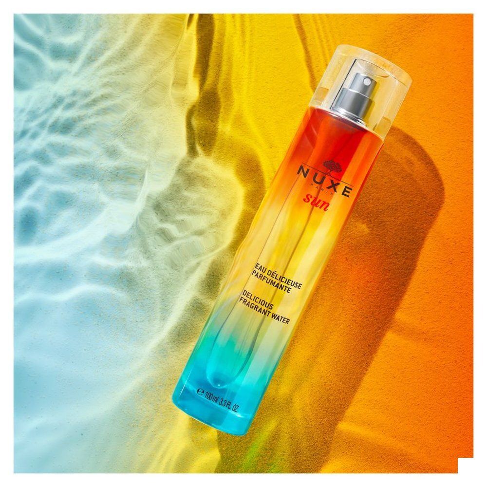 Zijaanzicht NUXE SUN Eau Délicieuse Parfumante fles met spraykop. Tekst op etiket.