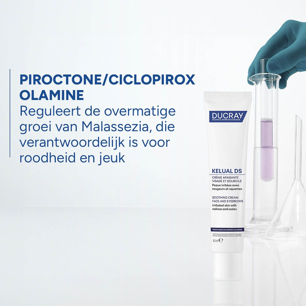 Witte tube met paarse opdruk, naast reageerbuizen met vloeistof. Tekst in het Nederlands.