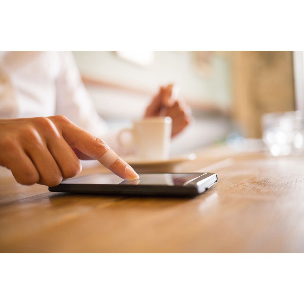 Rol Nexcare textieltape. Rode kern, beige tape. Tape wordt afgerold.