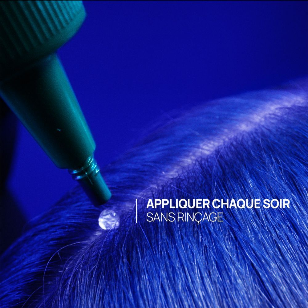 Applicateur vert déposant un liquide clair sur des cheveux bleus.