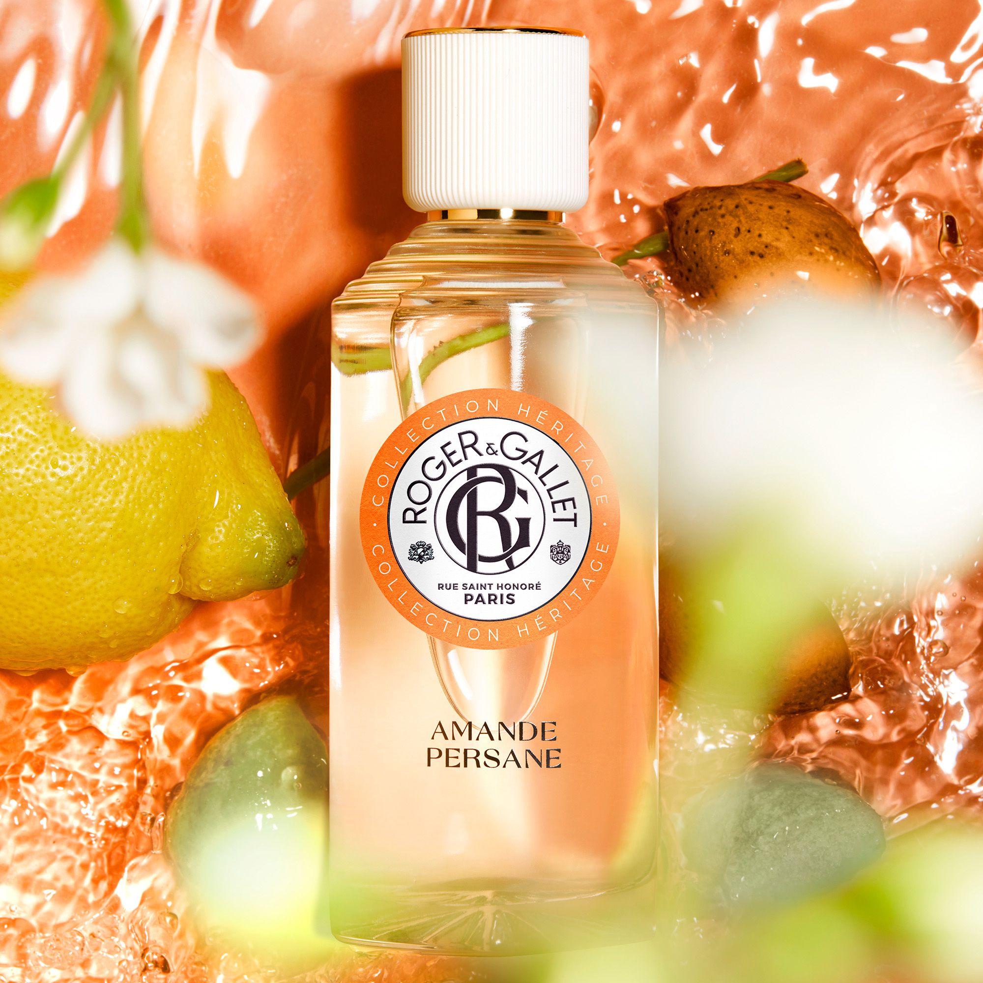 Glazen fles, productnaam: Amande Persane. Beeldcompositie met fruit en water.