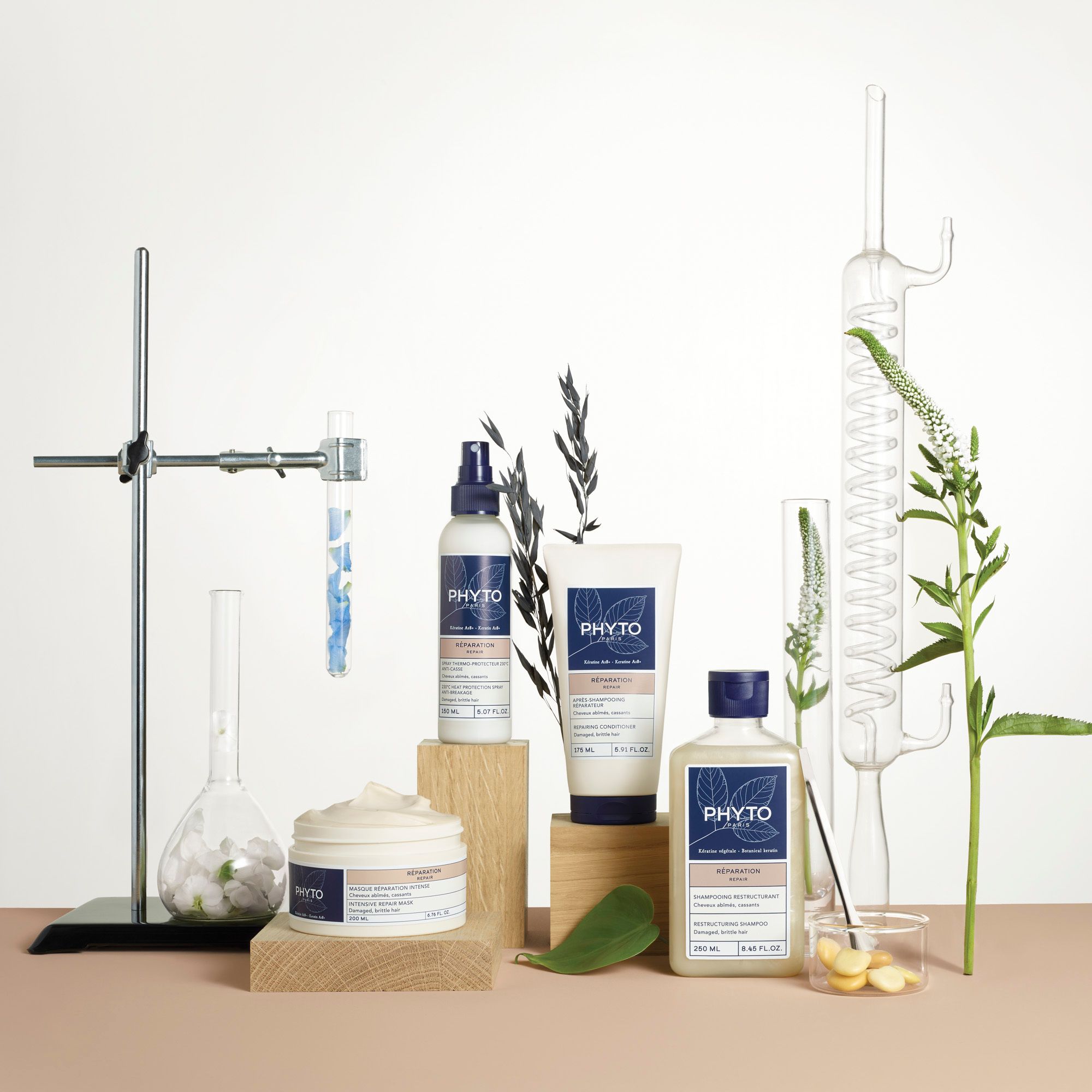 Meerdere productflessen en containers, omringd door planten en laboratoriumapparatuur.