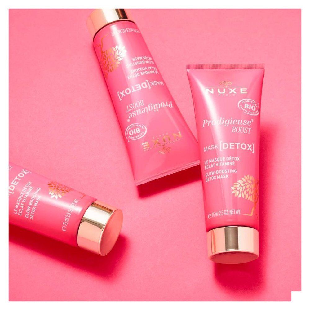 Drie NUXE Prodigieuse Boost Detox Masker tubes op roze achtergrond.