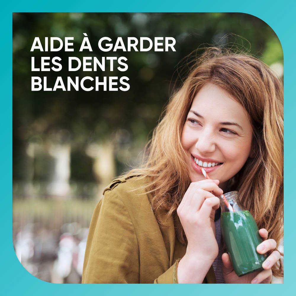 Femme buvant un smoothie vert. Aide à garder les dents blanches.