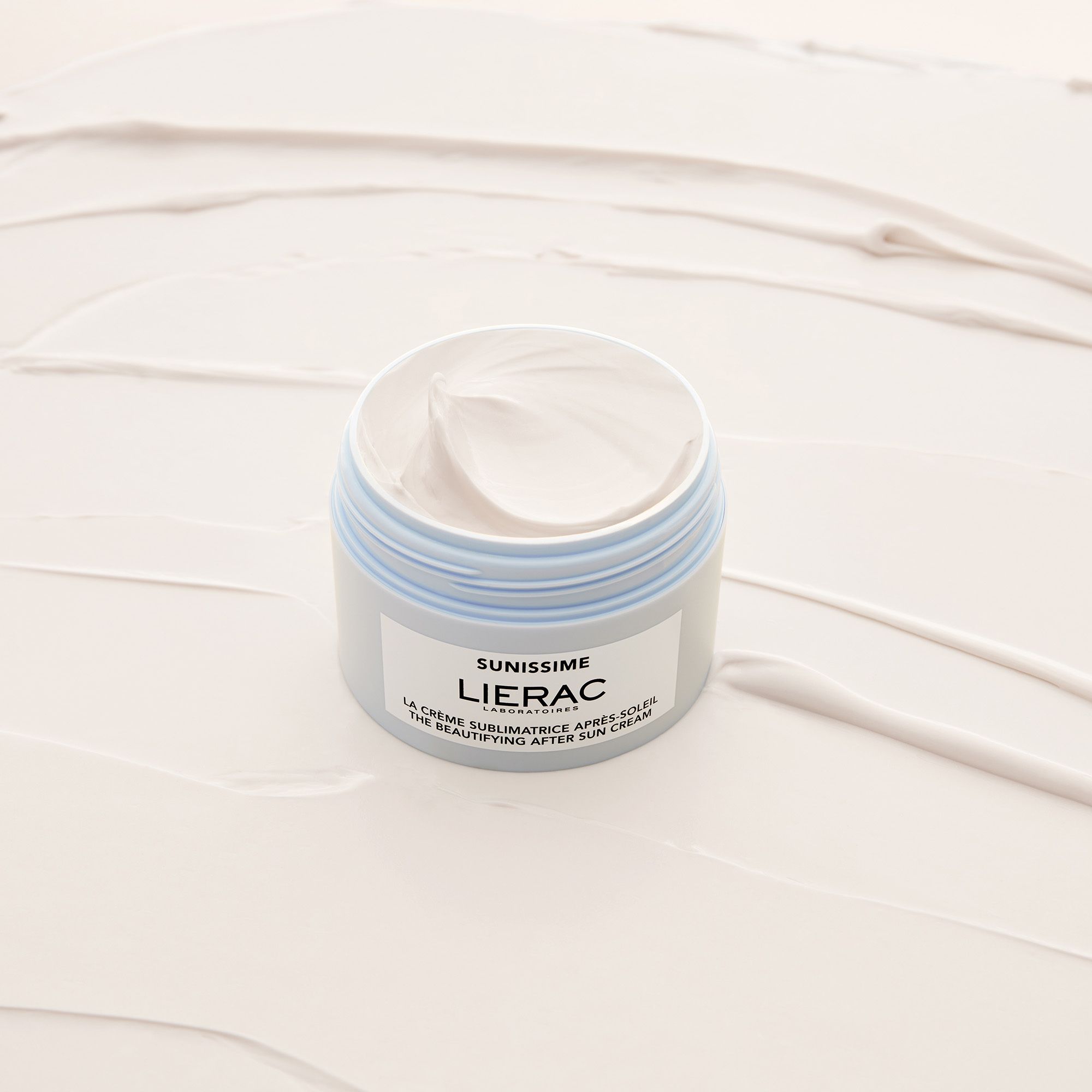 Crème dans un pot bleu clair avec couvercle noir. Inscription : Sunissime, Lierac. Texte : La crème sublimatrice après-soleil.