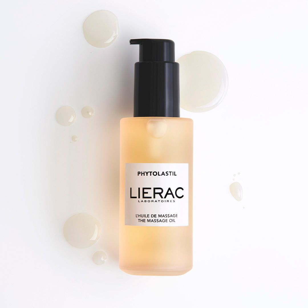 Beige fles met zwarte pomp. Tekst: Lierac, Phytolastil, massageolie. Druppels ernaast.