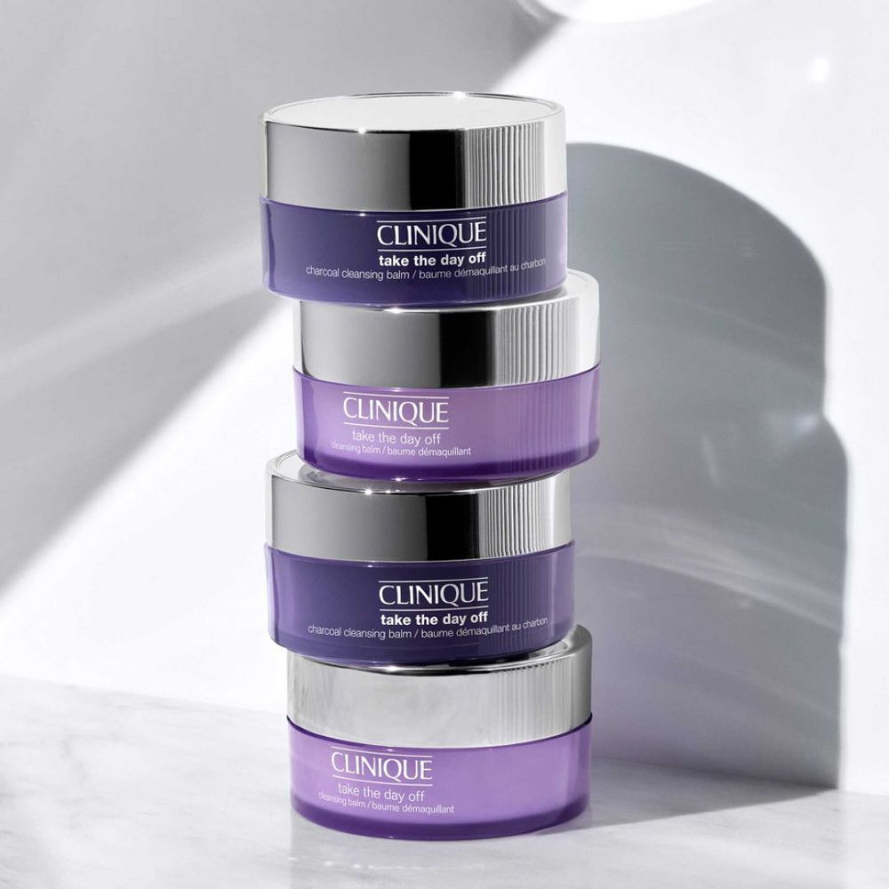 Vier potten CLINIQUE Take the Day Off, gestapeld. Paarse potten met zilveren deksels.