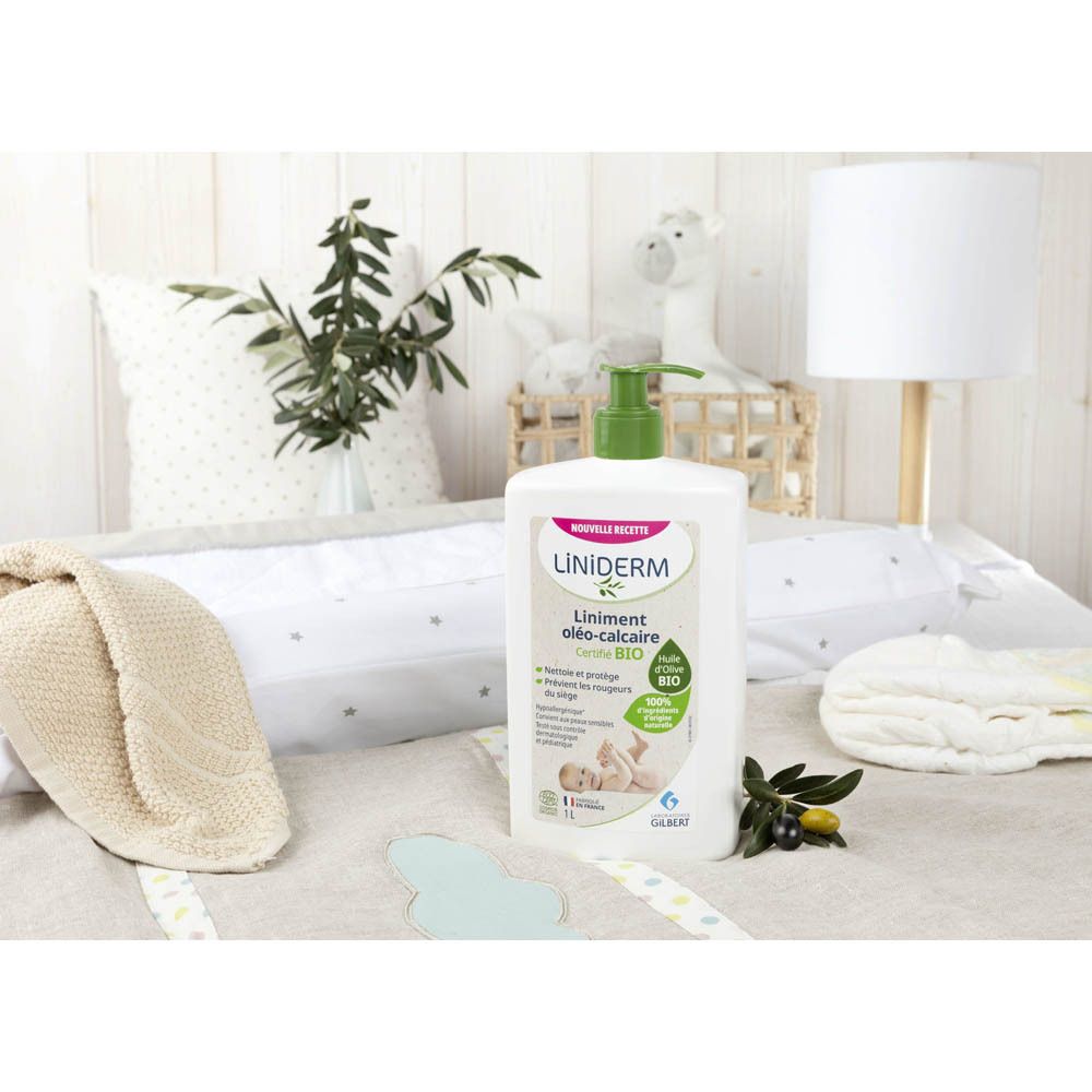 Witte fles met groene pomp op een aankleedkussen. Omgeving: kussens, deken, speelgoed. Opschrift: Liniderm.