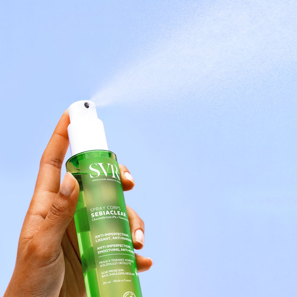 Hand houdt groene fles met witte spraykop. Spraynevel. SVR Sebiaclear Spray Corps.