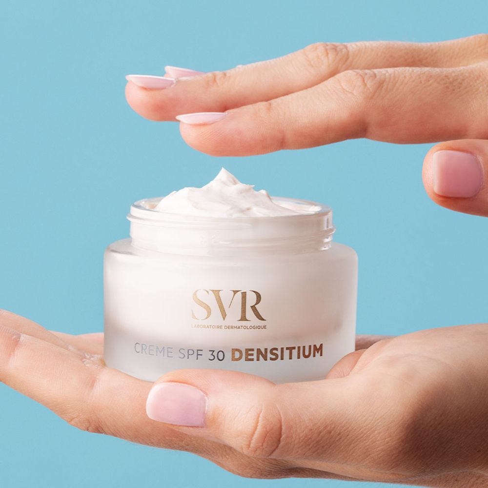 Handen houden een crèmepot vast. Opschrift: SVR, Crème SPF 30 DENSITIUM. Crème zichtbaar.