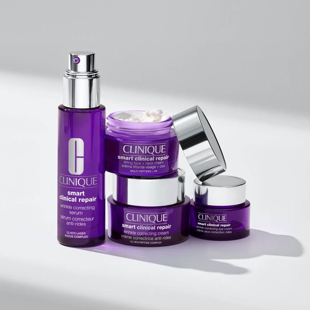 Clinique Moisture Surge Sheertint Hydrator SPF 25 in een lichtroze tube, omgeven door water en make-up textuur.