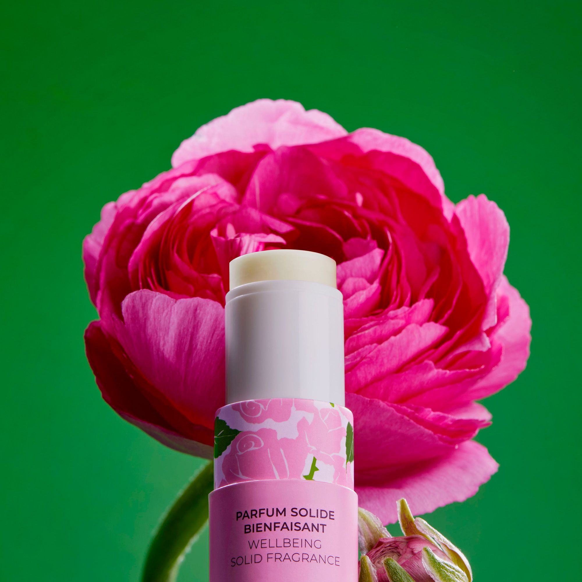 Product in verpakking, voor roze bloem. Logo en tekst: Roger&Gallet, Parfum Solide, Wellbeing Solid Fragrance. Roze bloemblad.