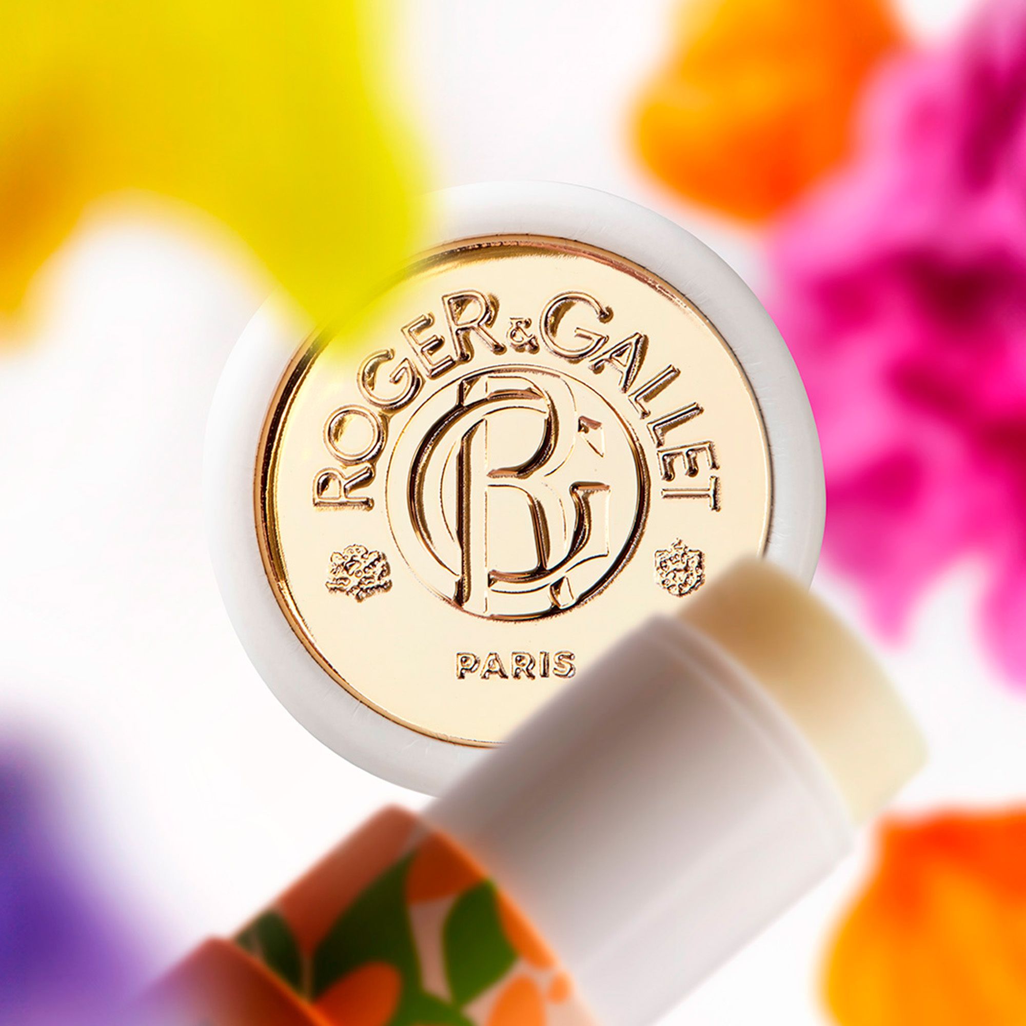 Produit vu de dessus, devant fleurs colorées. Logo et texte: Roger&Gallet. Couvercle doré. Produit visible.