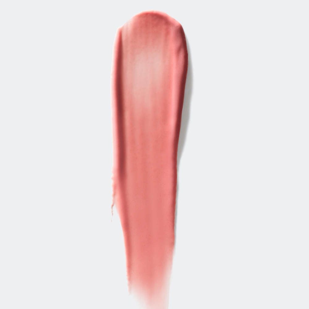 Een veeg romige, perzikkleurige lippenstift op een witte achtergrond.