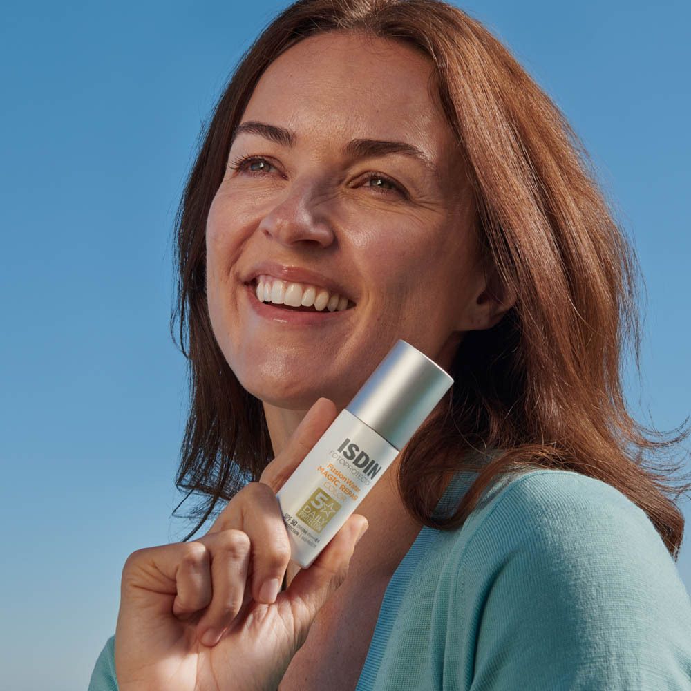 Vrouw met zonnecrème op haar gezicht. Blauwe lucht op de achtergrond.