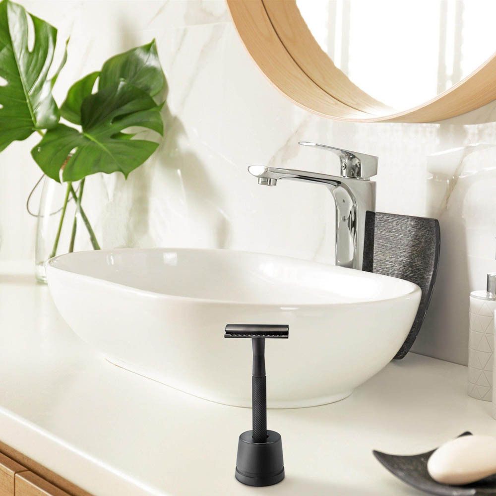 Rasoir et support noirs sur une surface blanche. Lavabo en arrière-plan.