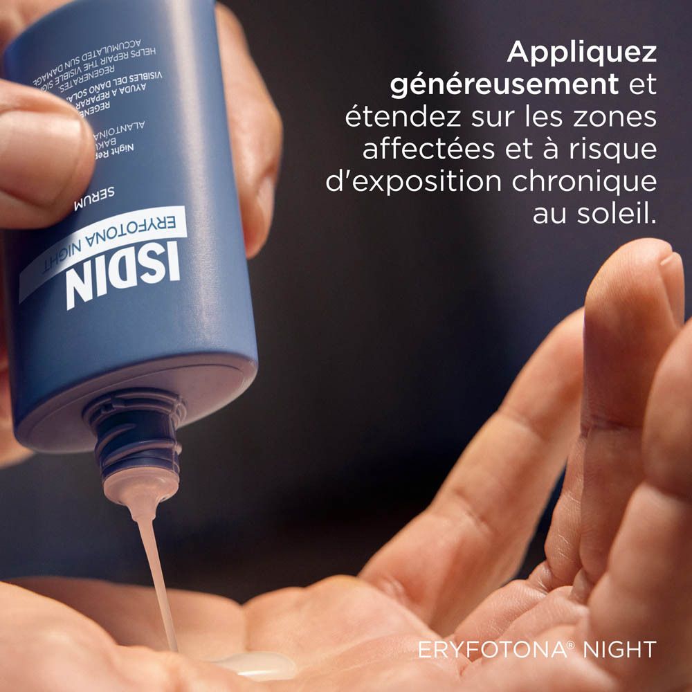 Main versant du sérum du flacon ISDIN Eryfotona Night Serum. Fond bleu.