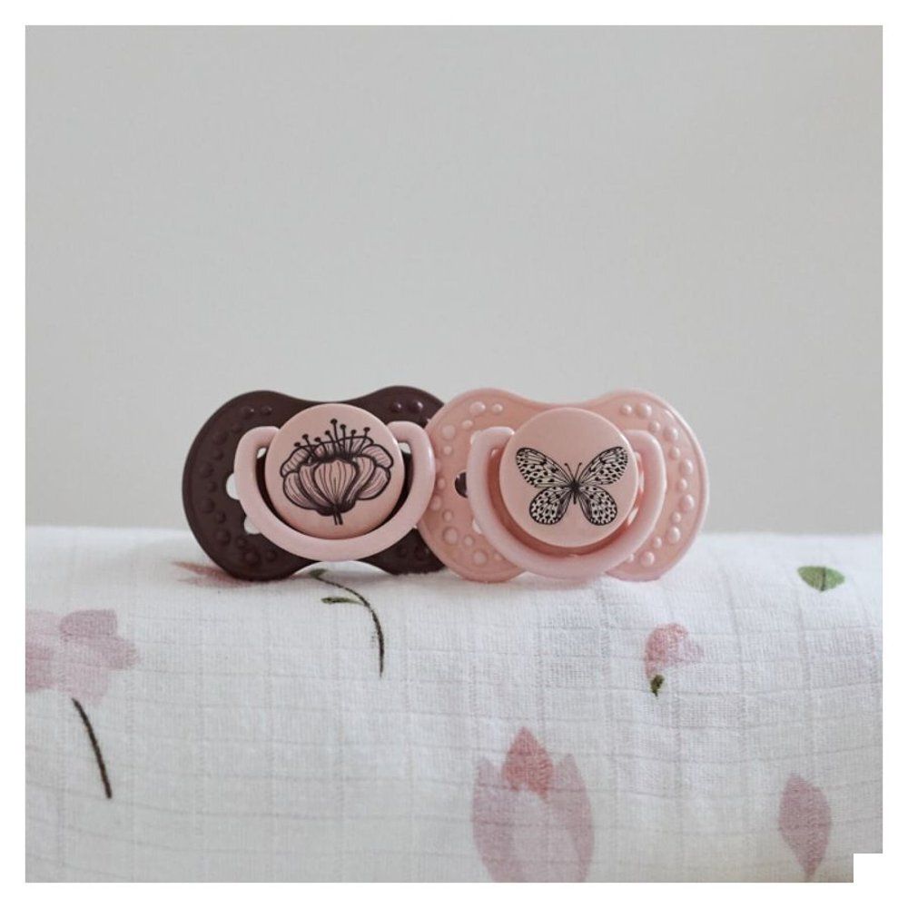 Emballage avec deux sucettes: Rose avec papillon, violette avec fleur. Pour 0-3 mois.