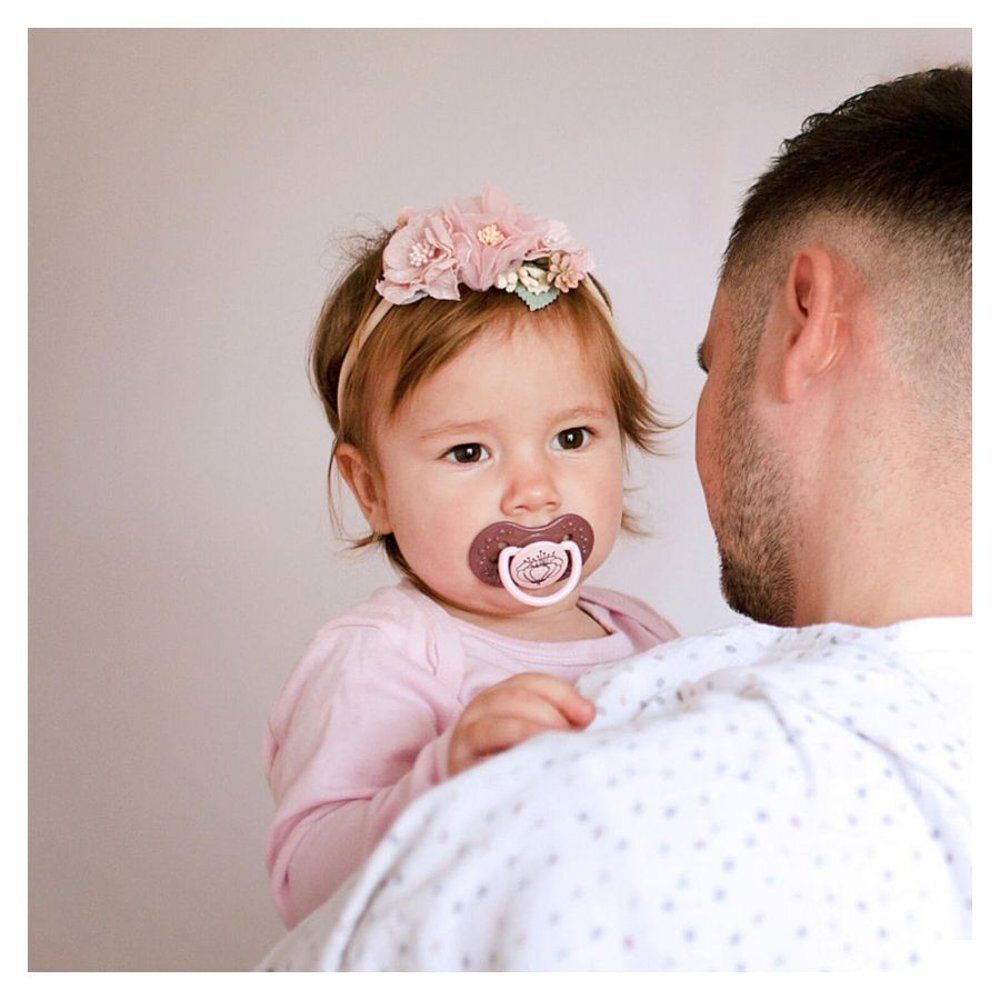 Bébé avec sucette et couverture. Sucette rose avec papillon.