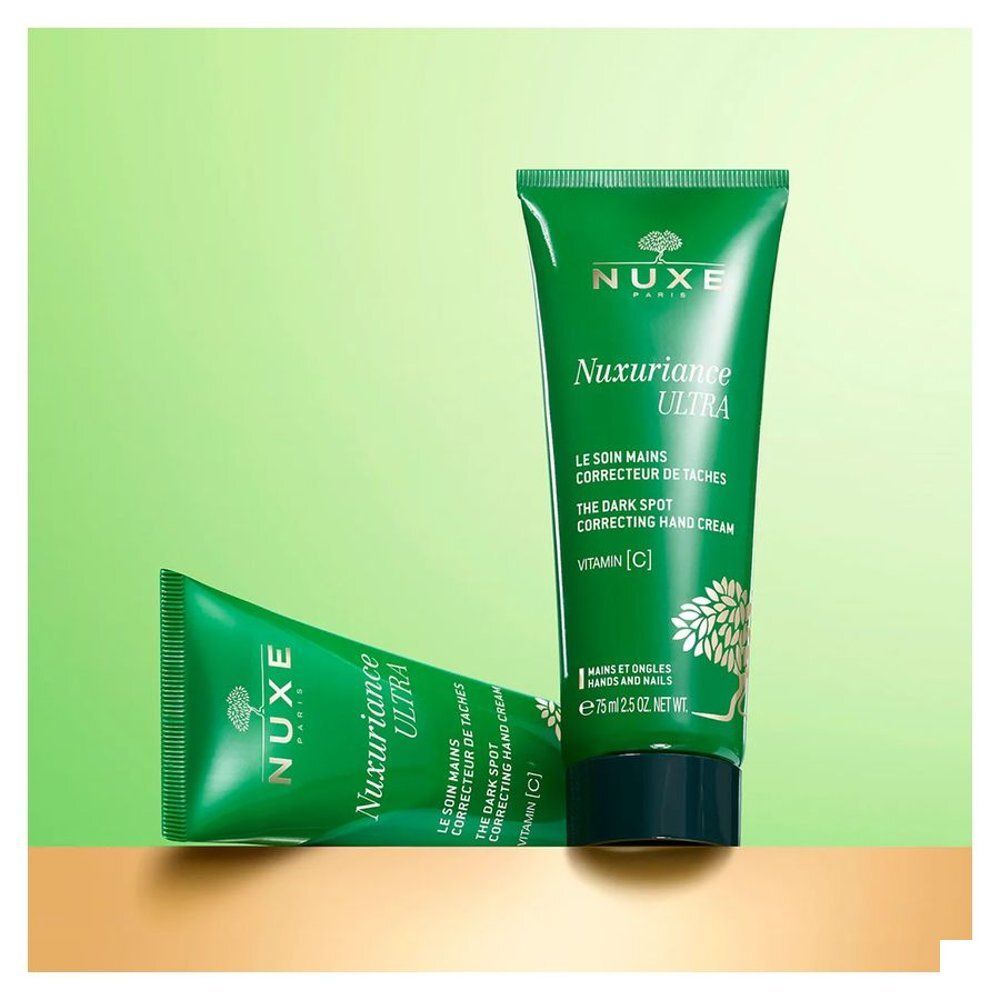 Twee groene tubes NUXE Nuxuriance Ultra Handcrème op een gouden en groene achtergrond.