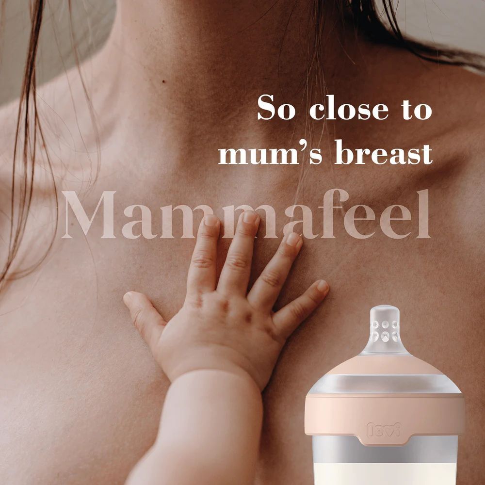 Babyhand raakt borst aan. Speen op de achtergrond. Tekst: So close to mum's breast, Mammalfeel.