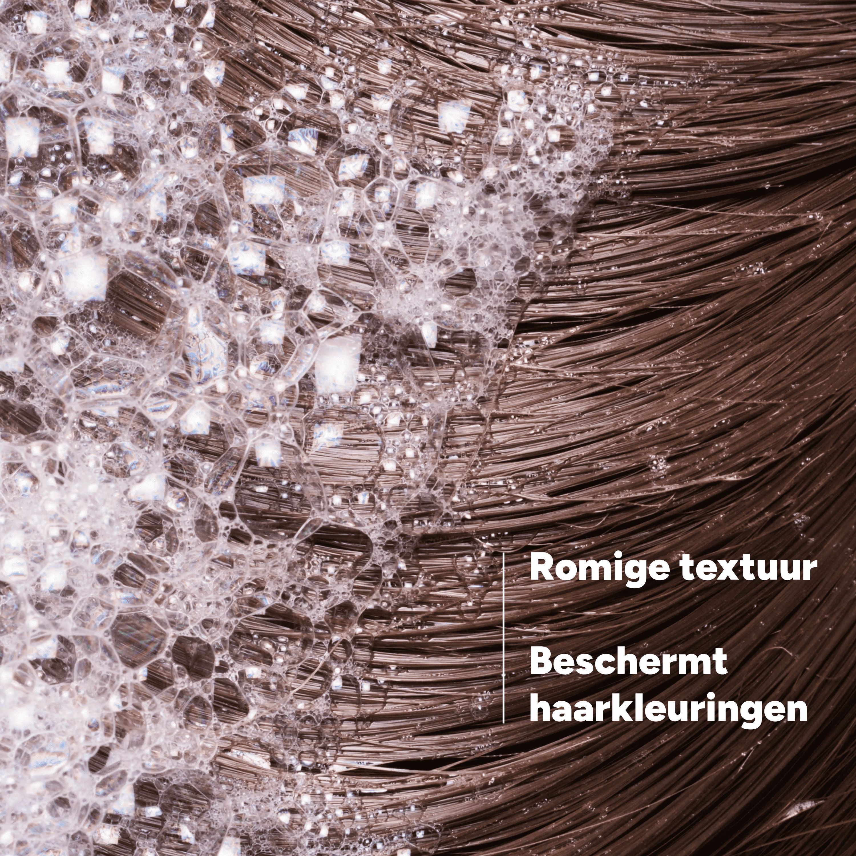 Close-up van bruin haar met schuim. Tekst: Romige textuur, beschermt haarkleuringen.