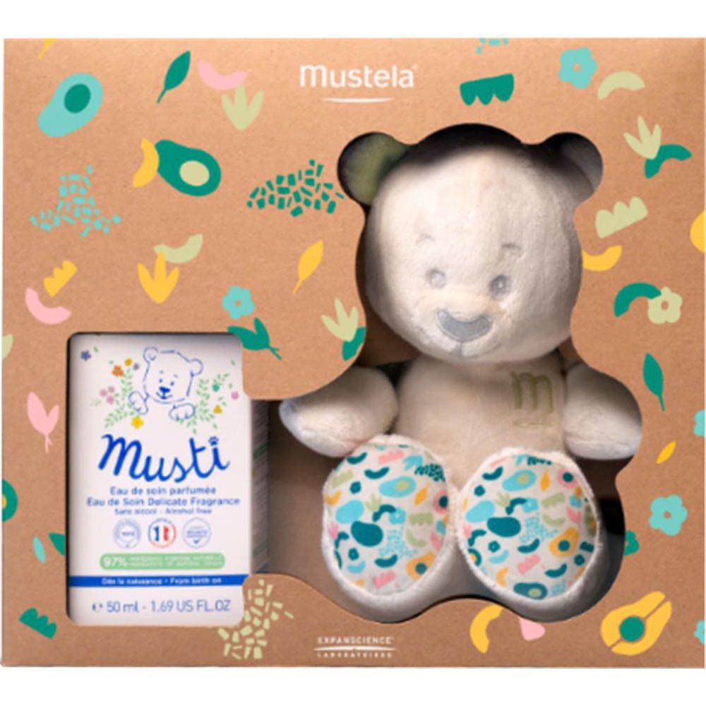 Coffret Mustela avec peluche ours et eau parfumée. L'ours a une oreille verte et des pattes colorées. La boîte est marron.