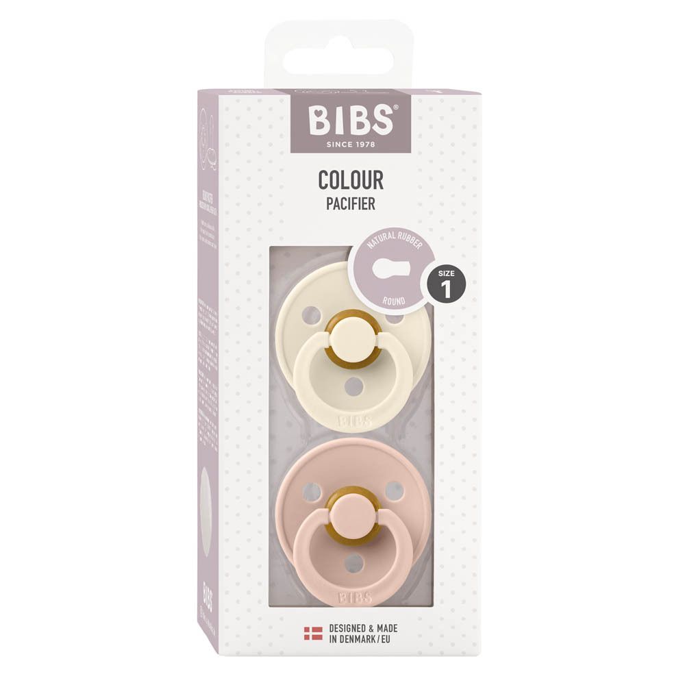 Verpakking met twee fopspenen. Merk BIBS. Ivoor en roze. Transparant venster. Tekst: Colour Pacifier, maat 1.