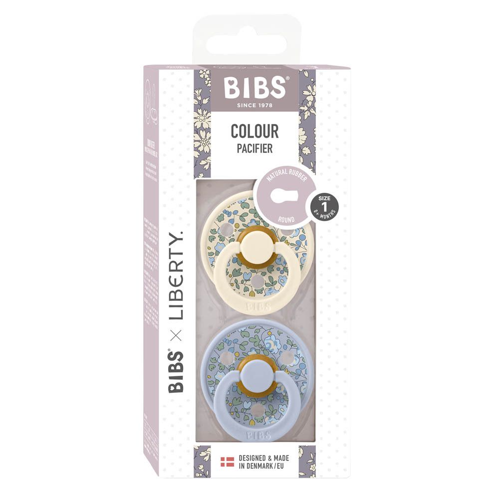 Verpakking met twee BIBS x Liberty fopspenen. Lichtblauw en crème met bloemenpatroon. Maat 1, 0-6 maanden.