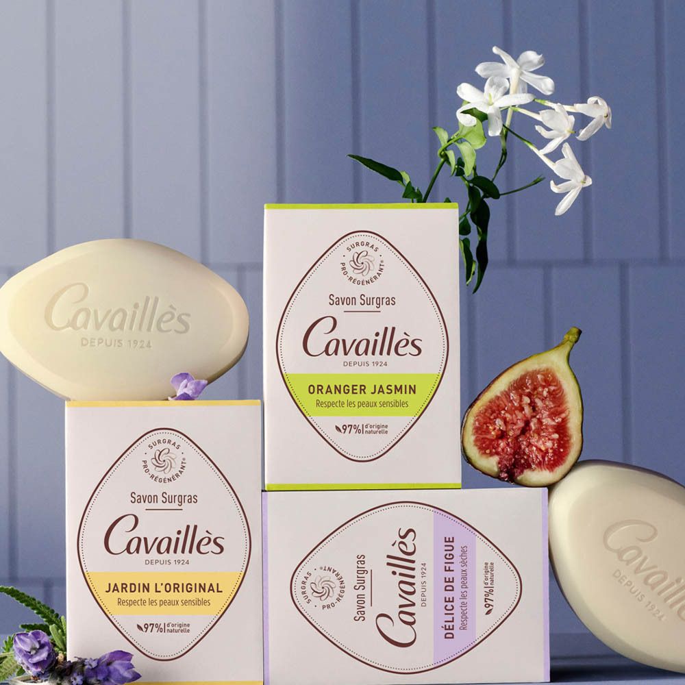 Trois savons et trois boîtes Cavaillès. Une figue et des fleurs sont également sur la table.