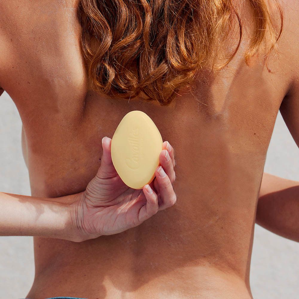 Gele ovale zeep, vastgehouden achter de rug van een persoon.