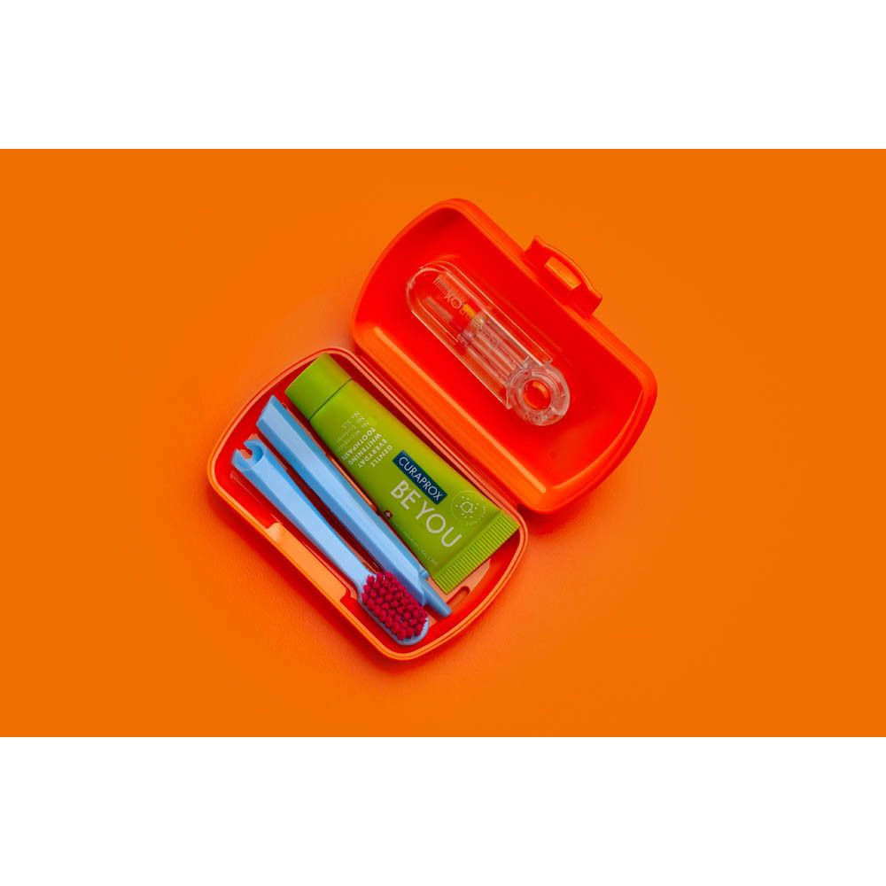 Étui de voyage orange avec brosse à dents, dentifrice et fil dentaire.