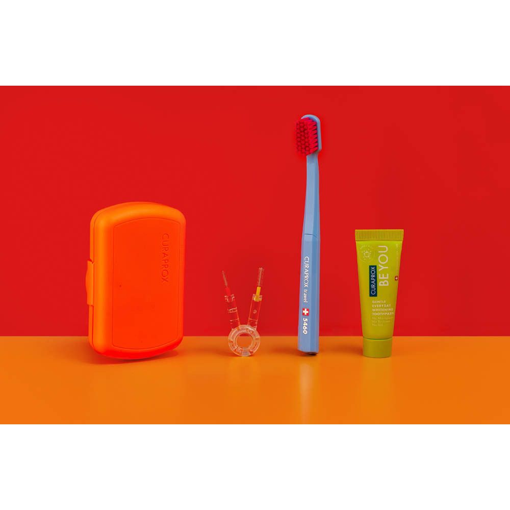 Een blauwe Curaprox tandenborstelset met tandpastatube, interdentale borsteltjes en oranje opbergdoosje.