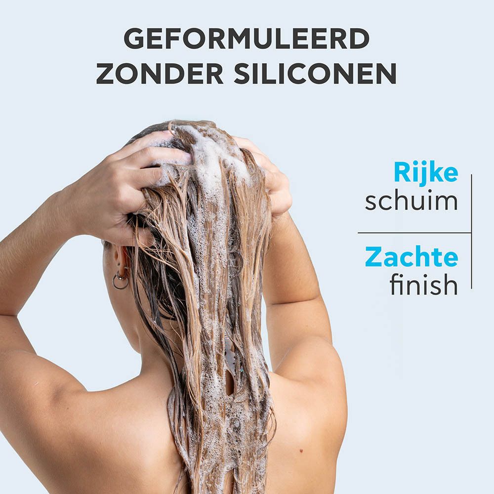 Vrouw wast haar haar met shampoo. Tekst: Geformuleerd zonder siliconen, Rijke schuim, Zachte finish.