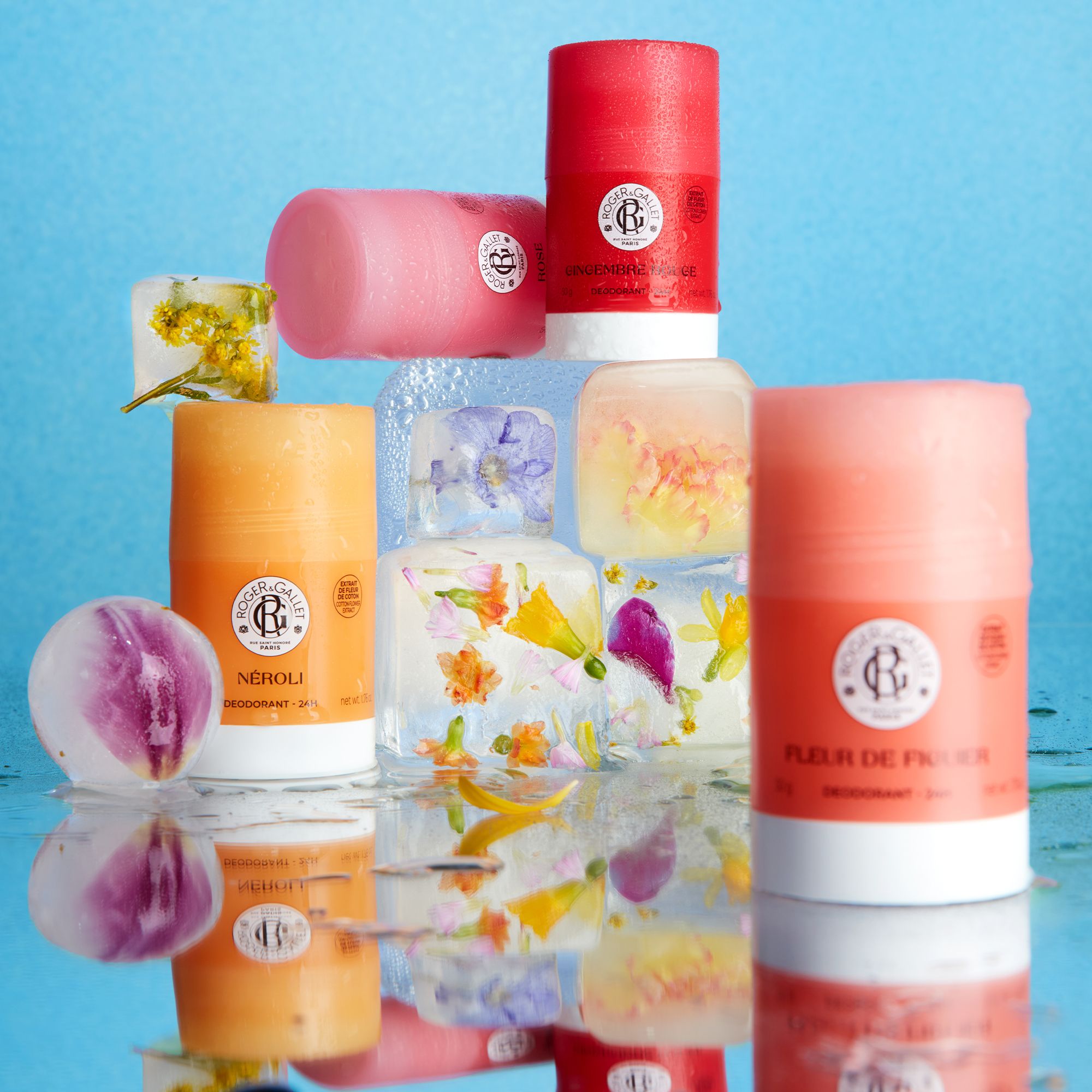 Verschillende deodorantsticks in verschillende kleuren, omringd door ijsblokjes met bloemen.