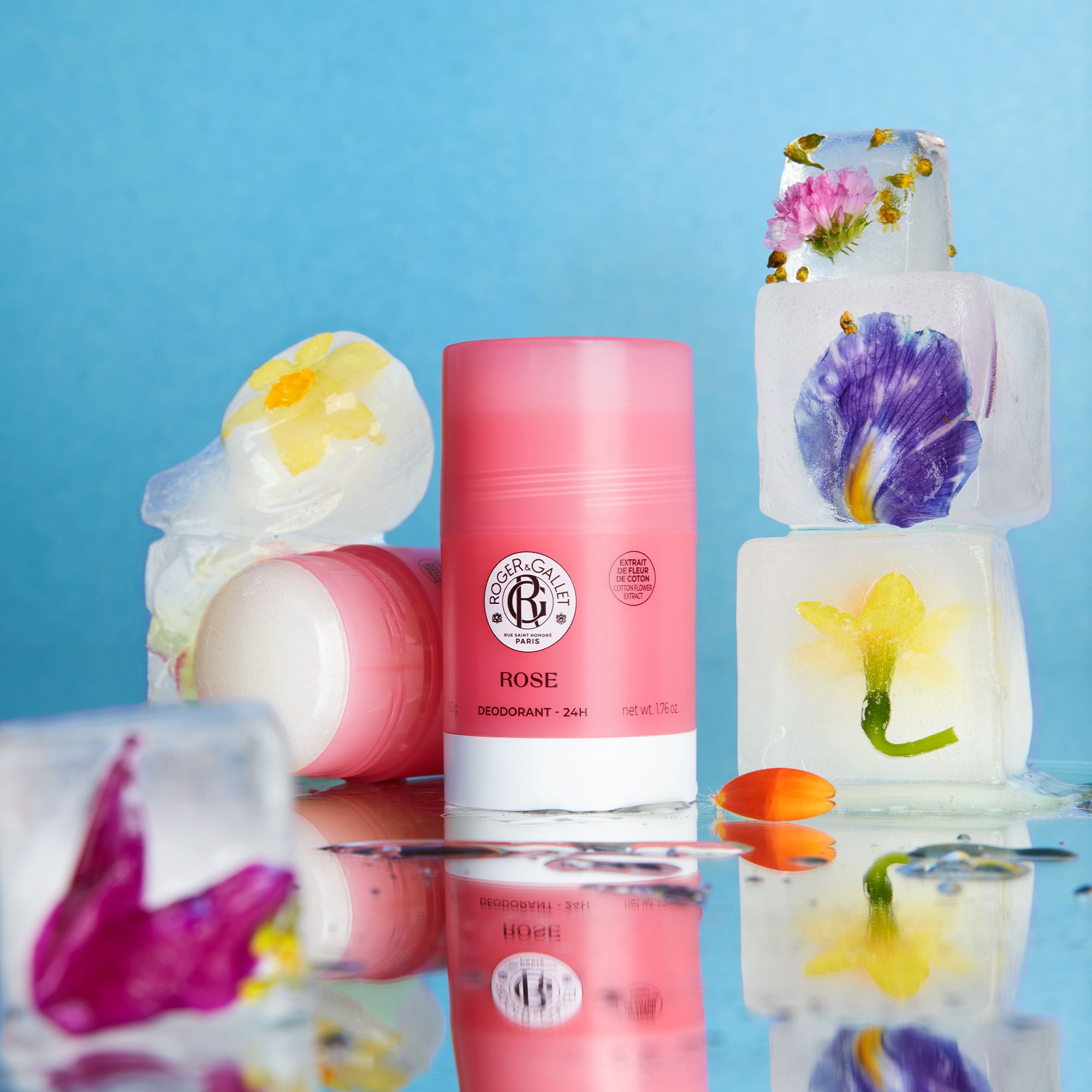 Een roze deodorantstick, omringd door ijsblokjes met bloemen.