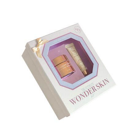Schuin geplaatste geschenkverpakking met twee cosmetische producten. Roze gouden pot en tube. Opschrift: The Ultimate Wonder Skin Kit.