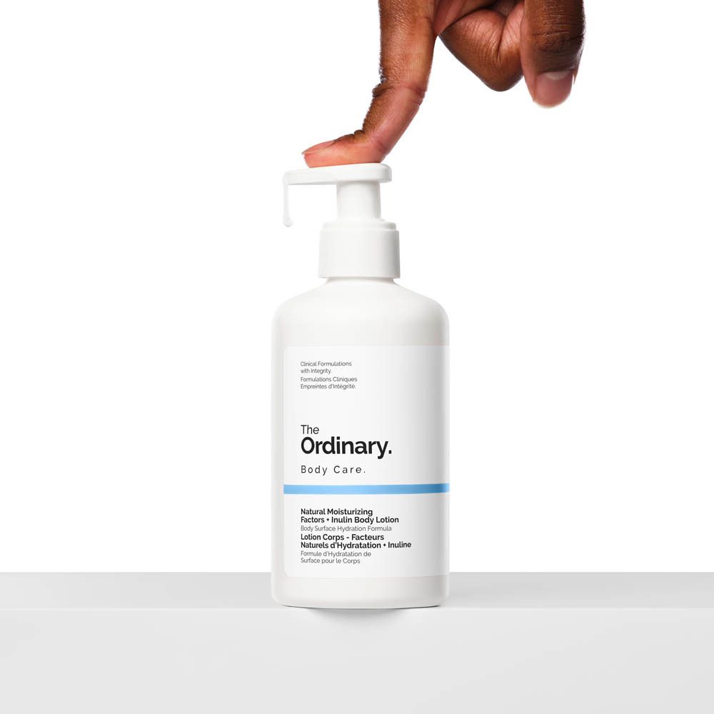 Flacon blanc avec pompe. Main appuyant sur le distributeur. Inscription : The Ordinary, Body Care.