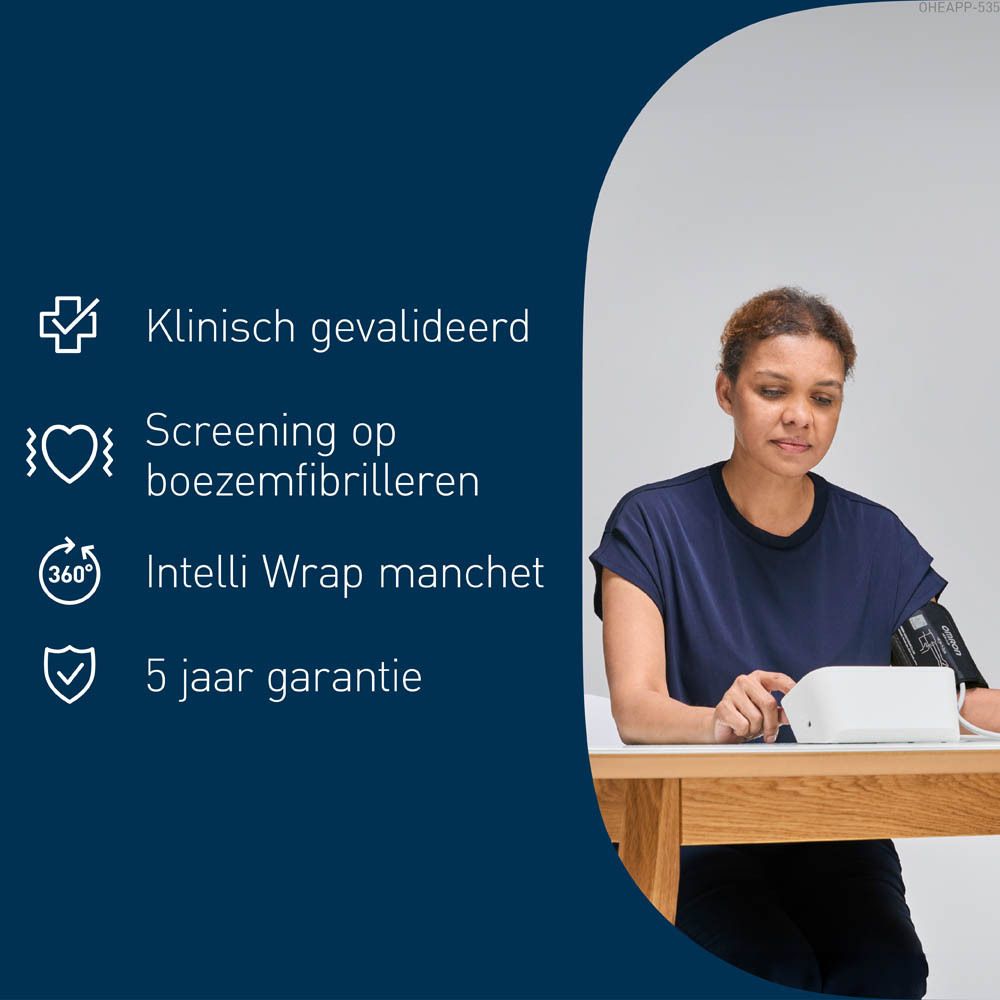 Een vrouw gebruikt een OMRON M6 Comfort AFib bloeddrukmeter. Ze zit aan een tafel. Het apparaat staat op de tafel.