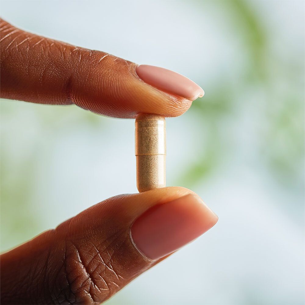 Een capsule tussen twee vingers. Beige capsule.