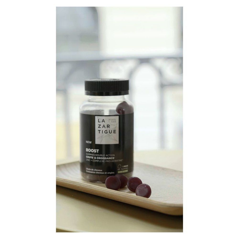 Flacon et gommes sur plateau en bois. Fond: fenêtres et rideaux. Inscription: LAZARTIGUE, BOOST.