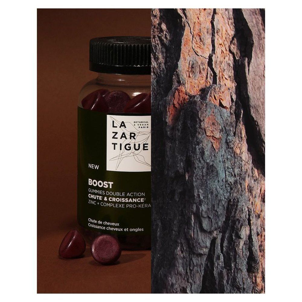 Fles en gummies naast boomschors. Opschrift: LAZARTIGUE, BOOST, Haaruitval & Groei.