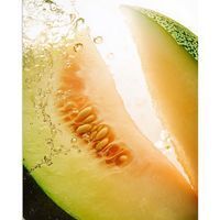 Melonenschijf. Vruchtvlees en zaden zichtbaar. Water spettert op de vrucht.