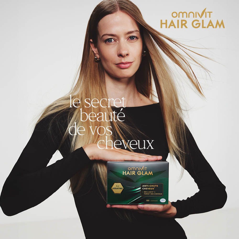 Femme tenant une boîte Omnivit Hair Glam. Longs cheveux blonds. Texte : « Le secret beauté de vos cheveux ».