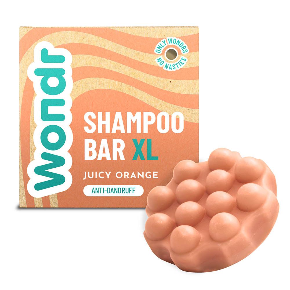 Kartonnen verpakking en shampoo bar. De bar is oranje en heeft een onregelmatige vorm.