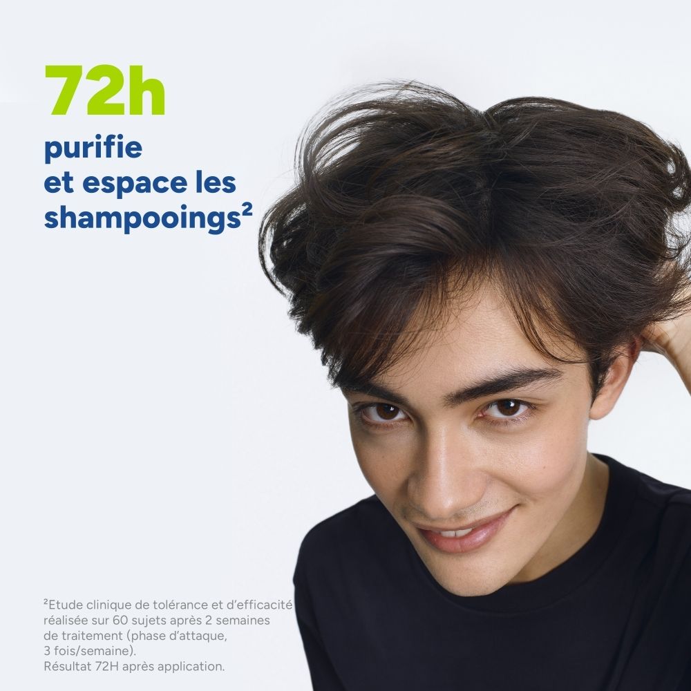 Gros plan sur un jeune homme aux cheveux volumineux, touchant ses cheveux. Texte sur 72 heures de purification et d'espacement des shampooings.
