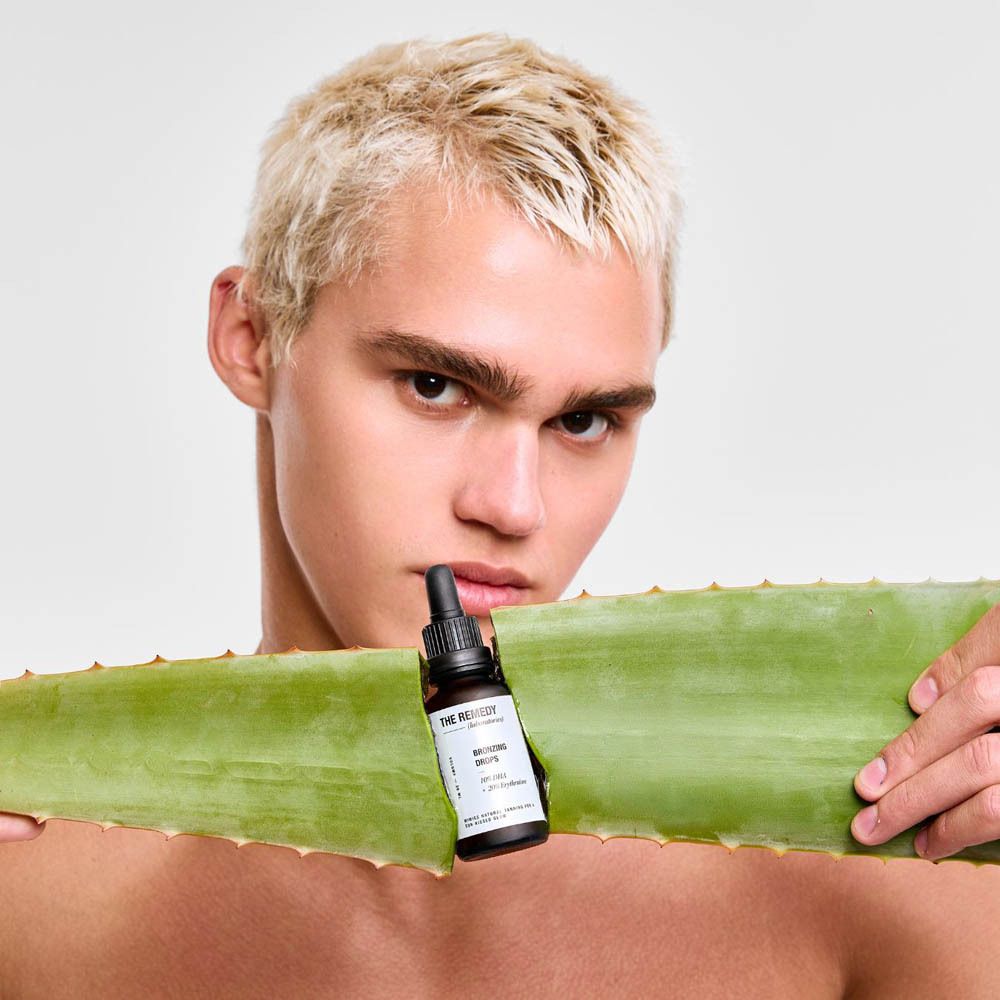 Homme tenant de l'Aloe Vera et le produit. Bronzing Drops. Flacon avec compte-gouttes.