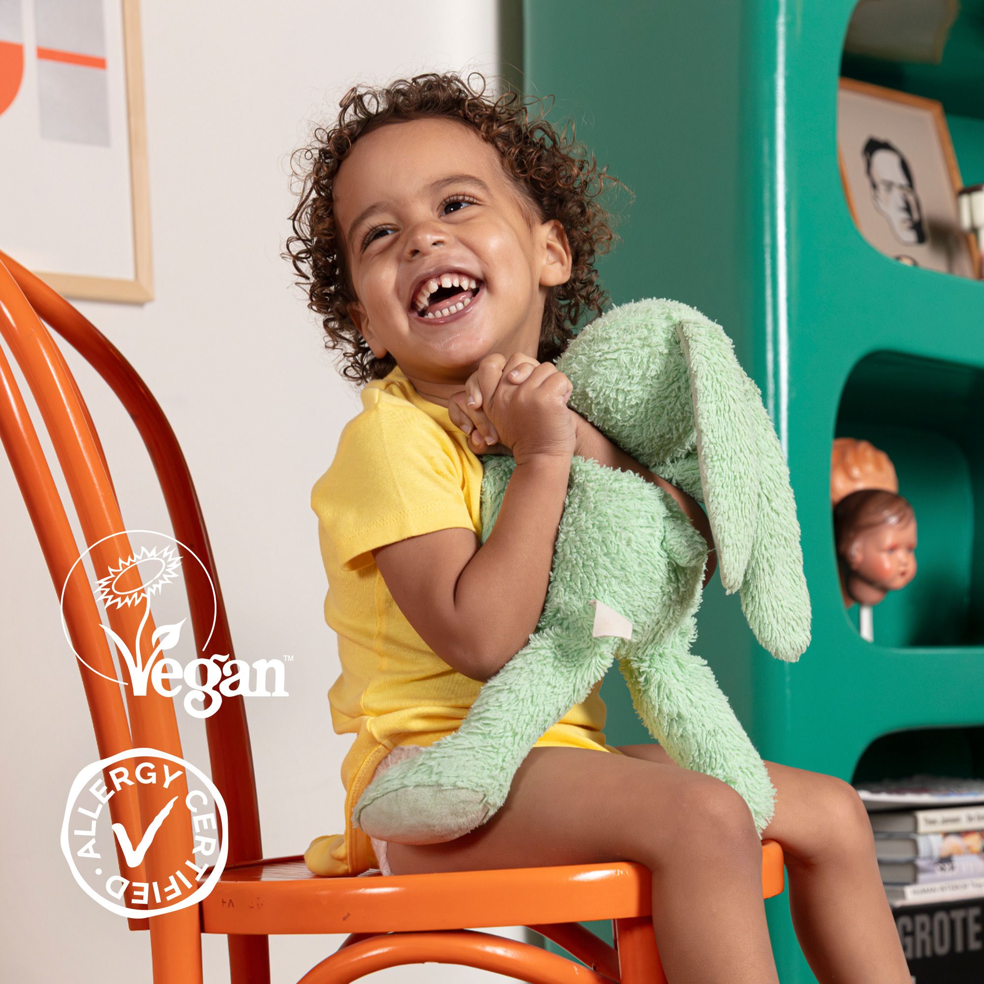 Enfant avec peluche. Sceaux Vegan et Allergy Certified visibles.