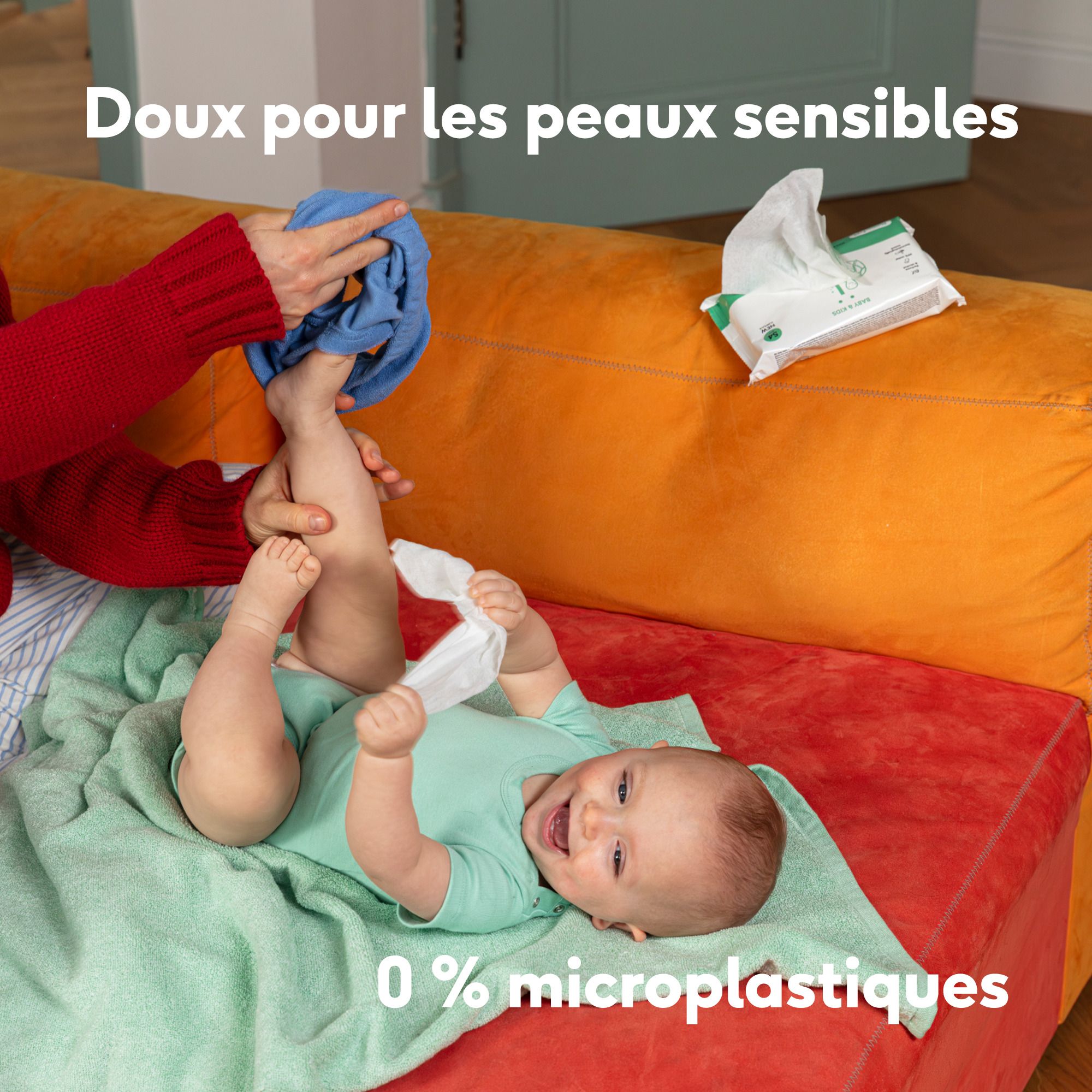 Pieds de bébé tenus par des mains. Texte: Alles wat je baby nodig heeft. Niets meer.