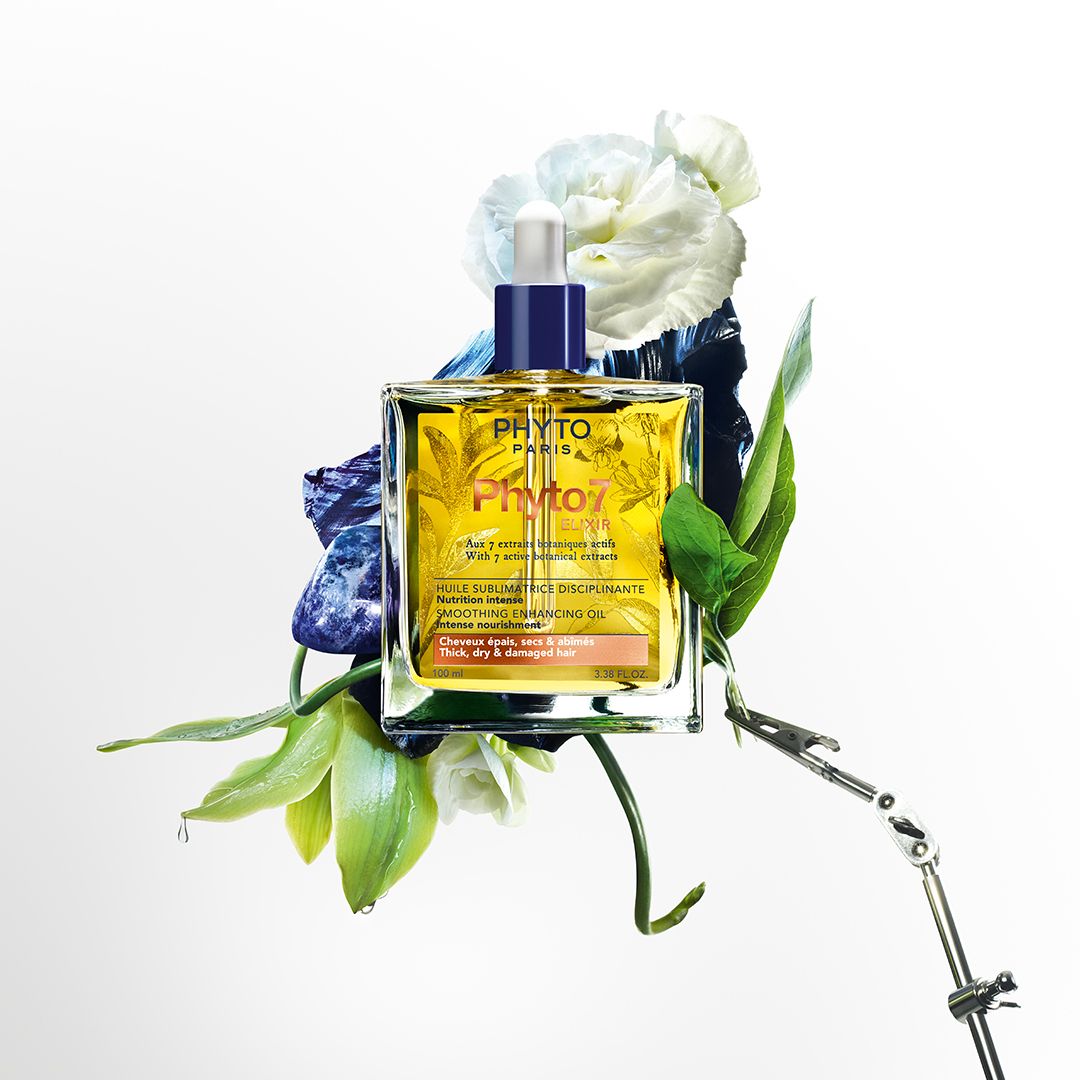 Glazen fles met gele vloeistof, omringd door bloemen en bladeren. Opschrift: Phyto Paris, Phyto 7 Elixir.